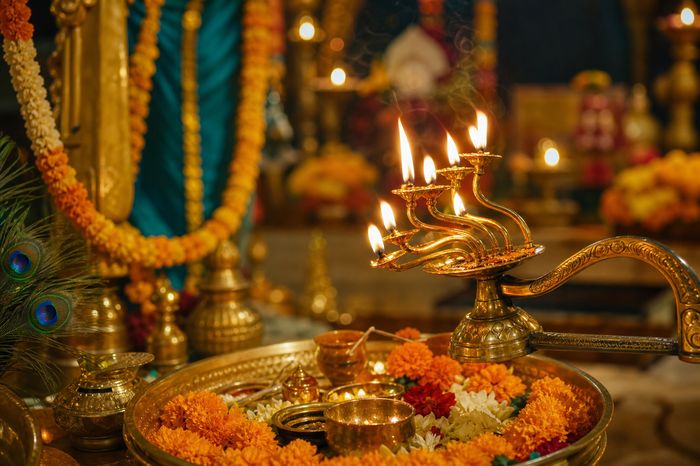 Folk Arti — multi-wick aarti lamp lit over a thali of marigolds and jasmine
